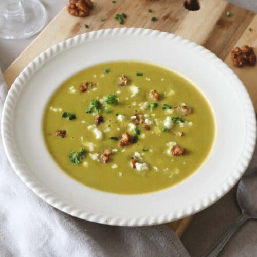 Creamy Asparagus Sweet Potato Soup with Feta cheese and Caramalised Walnuts in white bowl