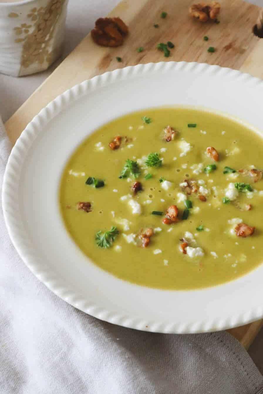 Asparagus Sweet Potato Soup with feta cheese and caramelized walnuts in white bowl