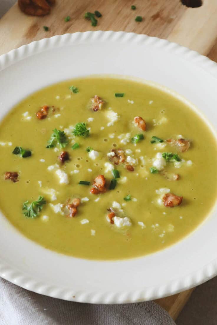 Sweet potato, asparagus soup with feta, caramelized walnuts and parsley in a while bowl close up