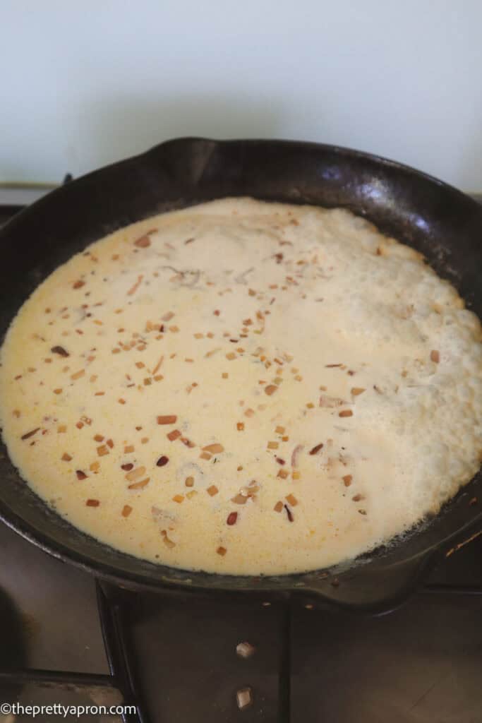 Shallots and cream boiling in black skillet