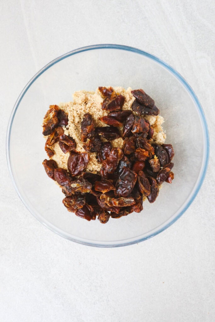 ground cashews, almonds and added dates in a glass bowl