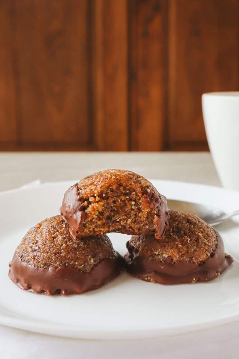 cashew almond chocolate balls on white plate with white cup in background