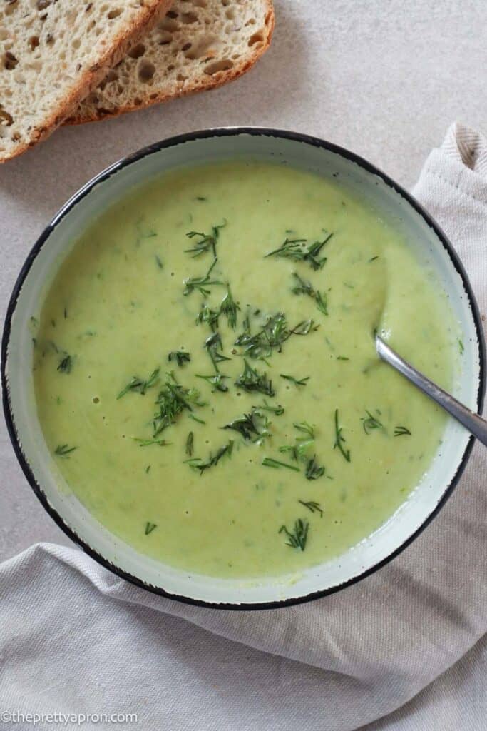 Asparagus dill soup in bowl with slices of rustic bread