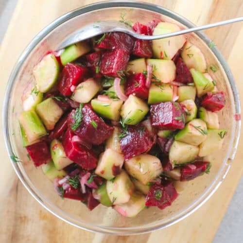 Beets and cucumbers in a glass bowl with dill lemon dressing