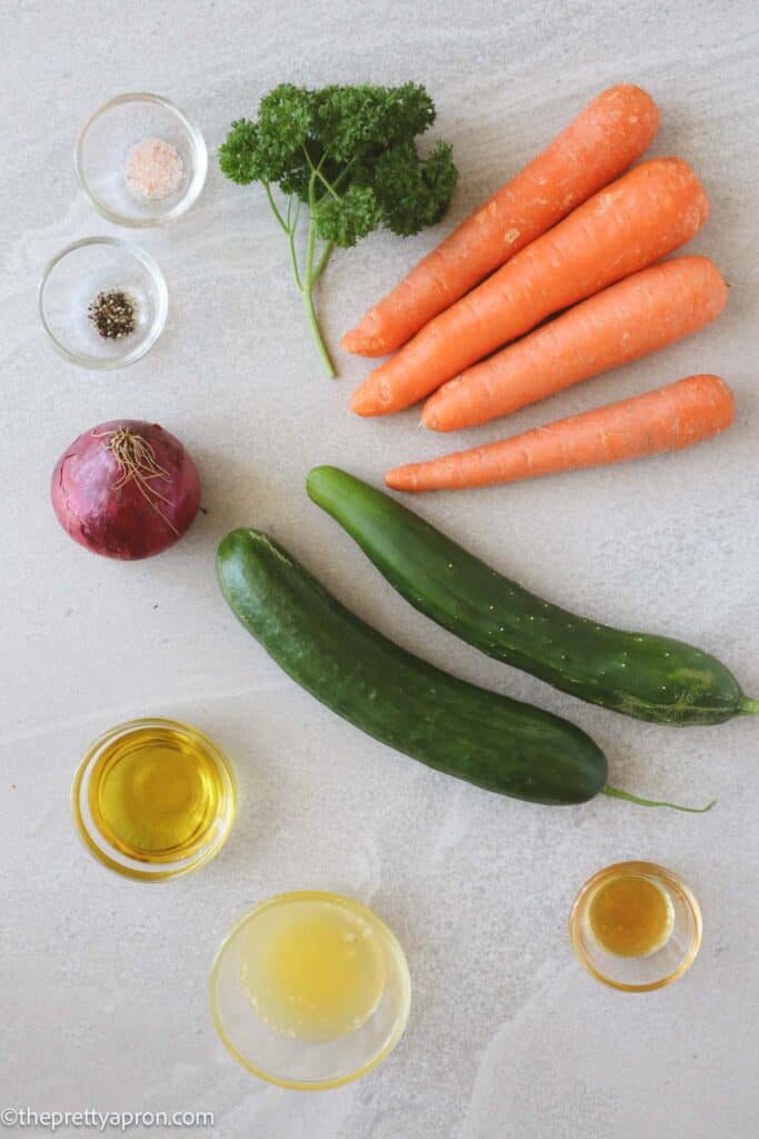 Ingredients for carrots cucumber salad including organic carrots, cucumbers, red onion, olive oil, lemon juice, honey, salt and pepper