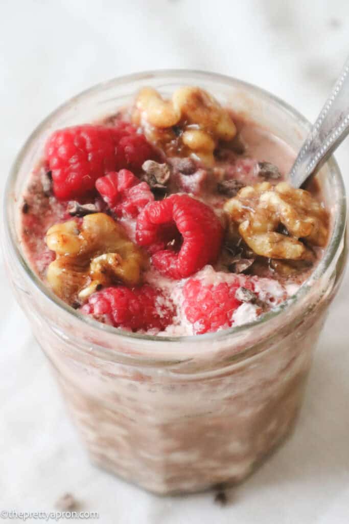 Chocolate, raspberries, oats, cocoa powder, milk and walnuts in glass jar