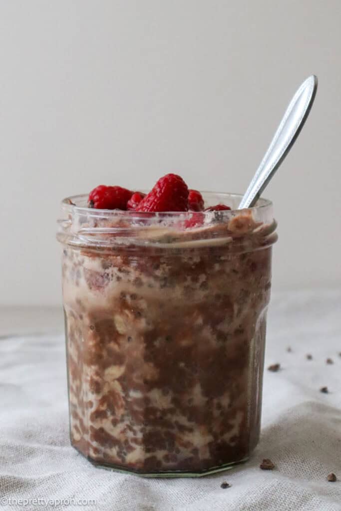 chocolate raspberry overnight oats in glass jar with spoon