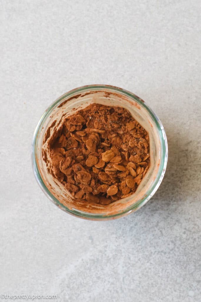 Jam jar filled with mixed up old fashioned oats, cacao powder and chia seeds