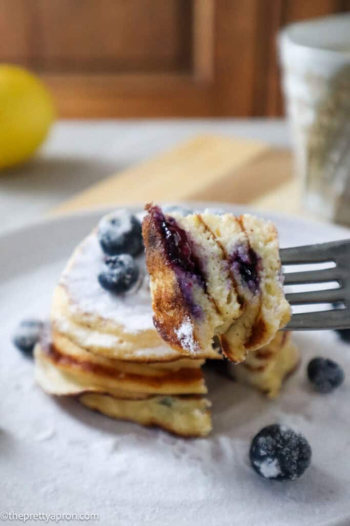 Fork holding bite of blueberry lemon ricotta pancakes