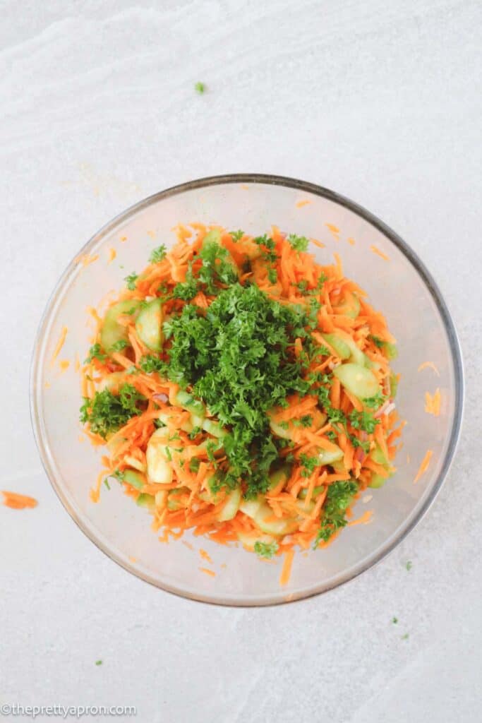 Carrots, cucumbers, red onions, parsley in glass bowl