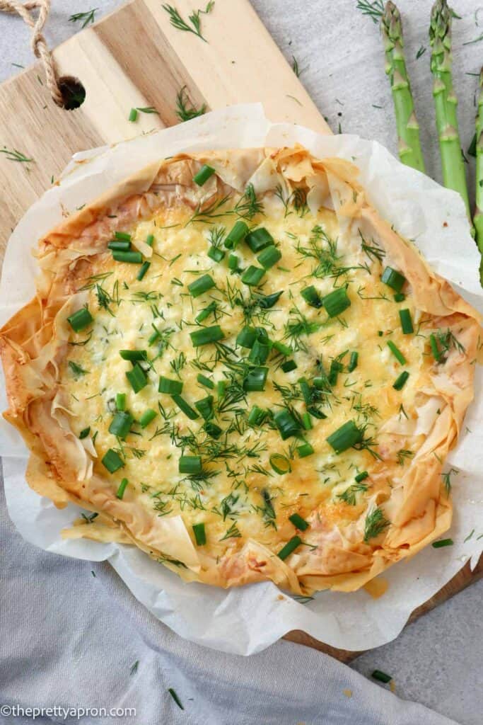 Asparagus Ricotta quiche with phyllo dough with a slice on a plate with salad and lemon ricotta dip
