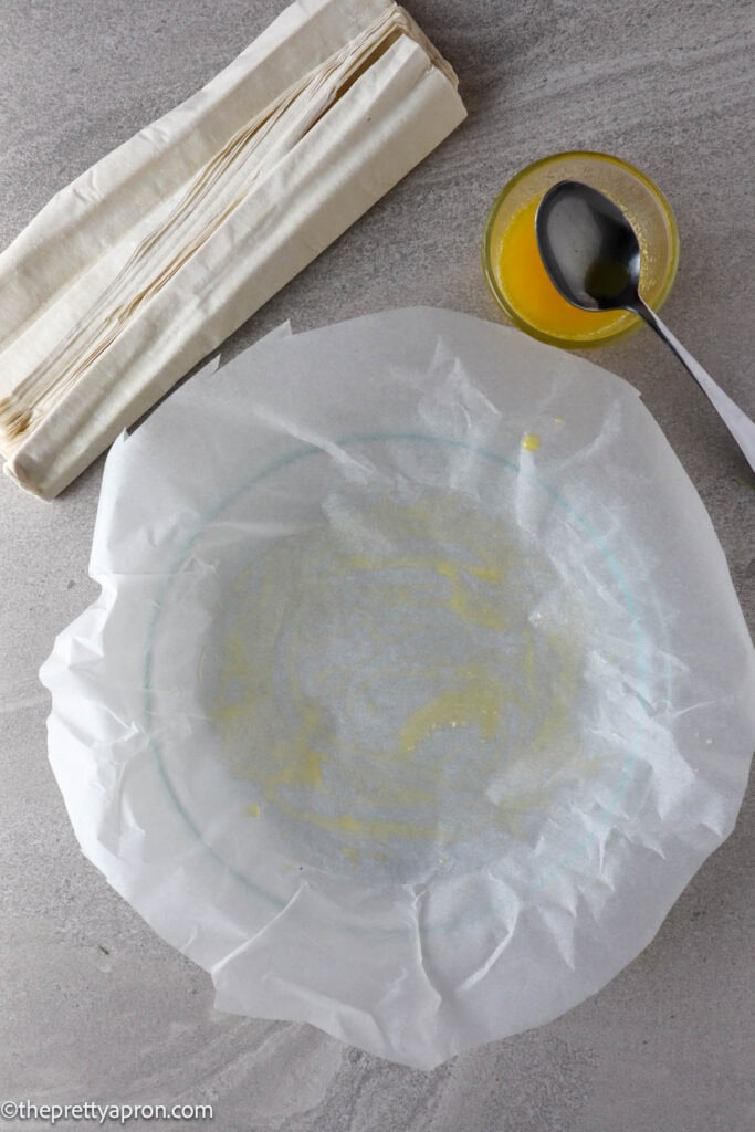 Baking paper with butter on quiche dish