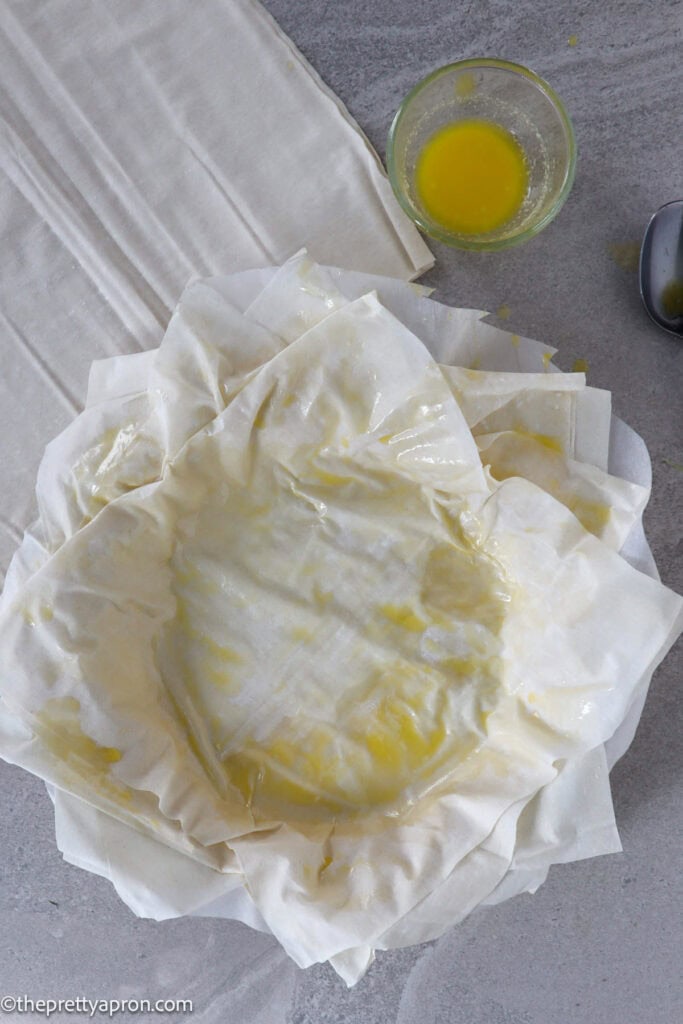 Pie dish with six sheets of phyllo dough and butter