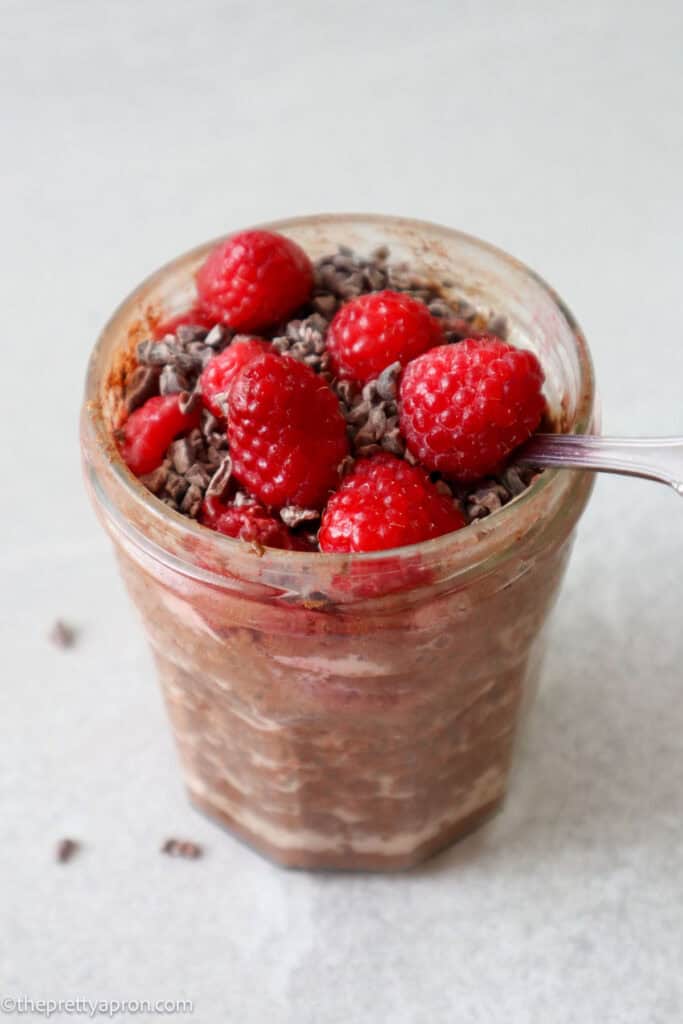 chocolate raspberry overnight oats in glass jar with spoon in mixture