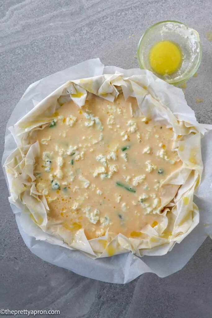 Phyllo dough in quiche dish filled with asparagus, ricotta cheese and eggs and feta cheese