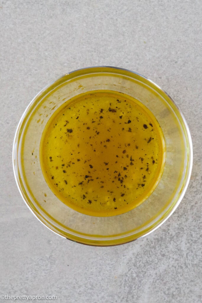 Lemon juice, extra virgin olive oil, salt and pepper in small glass bowl
