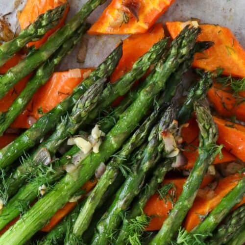 roasted asparagus and carrots on baking tray with fresh dill