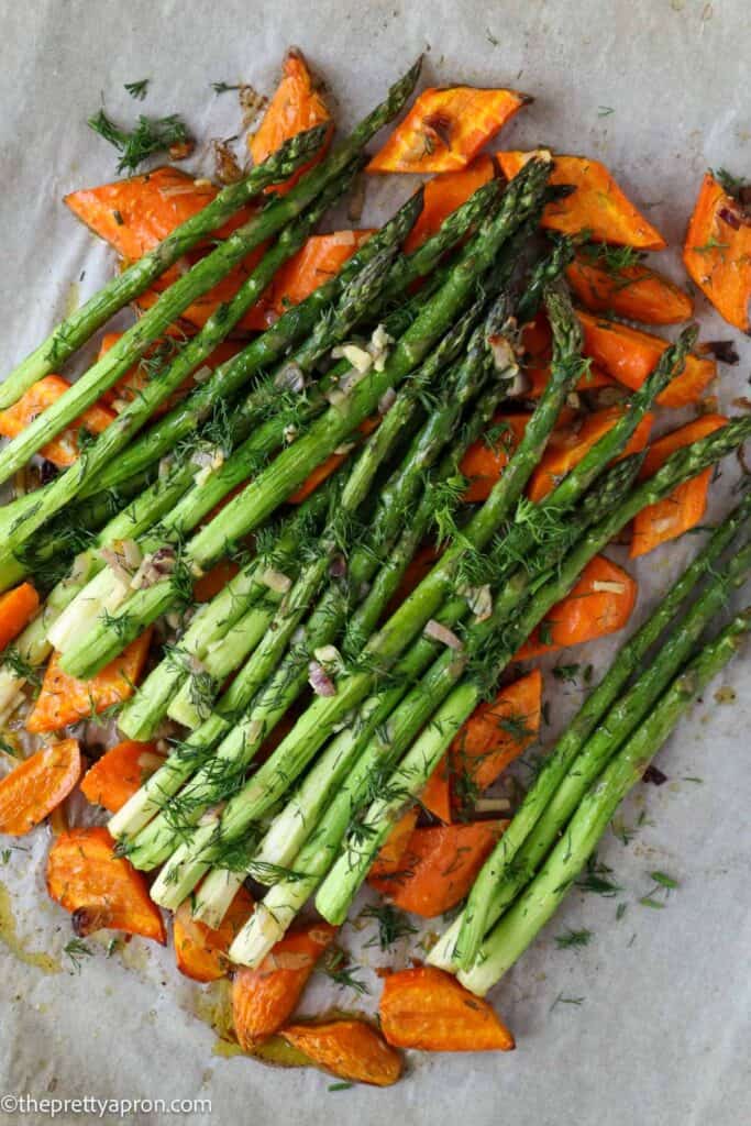 Roasted asparagus and carrots sprinkled with fresh dill on baking tray